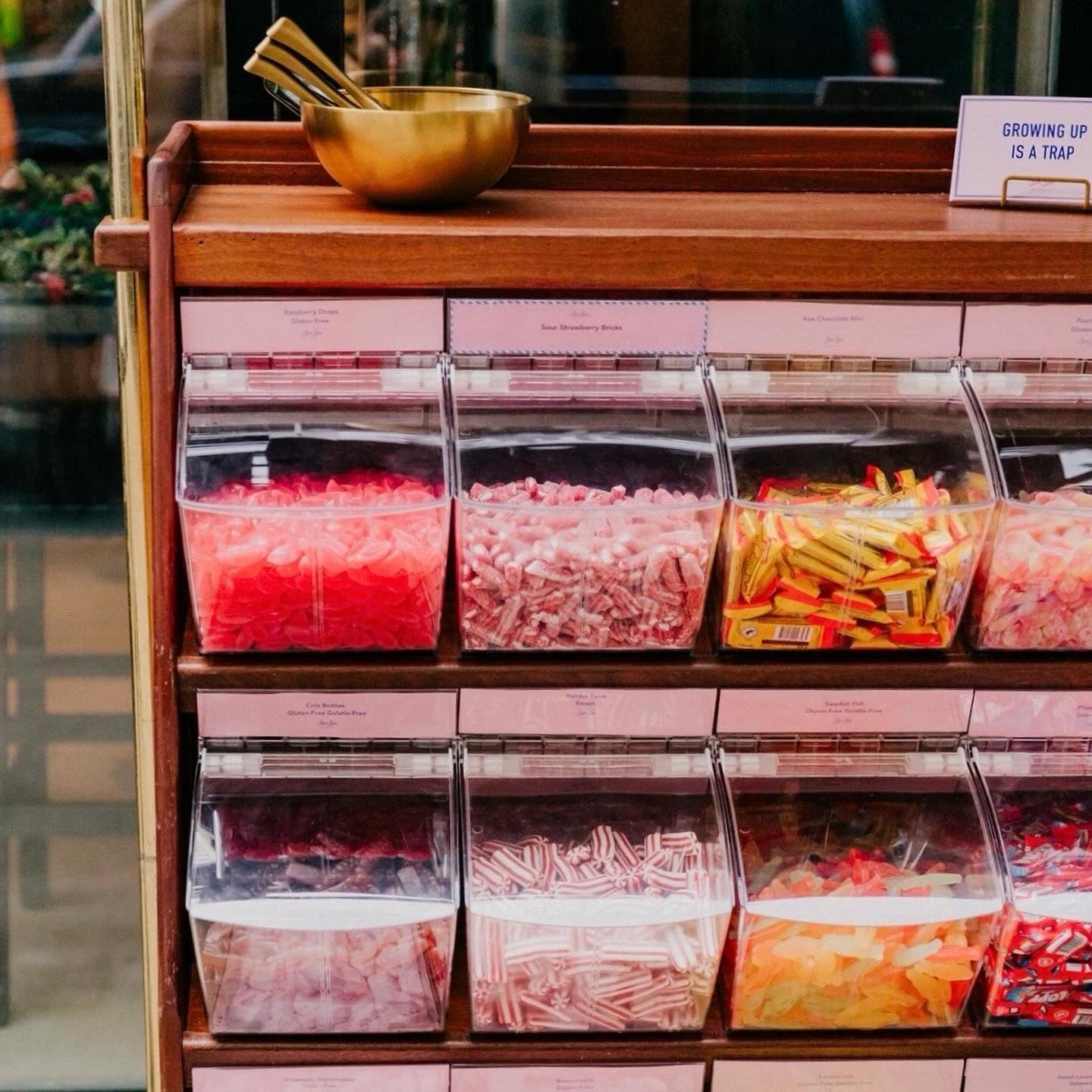 Close-up of acrylic bins filled with pink, red and orange candy