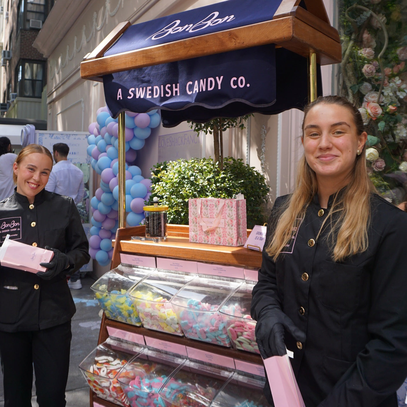Two BonBon candy sommeliers in black jackets beside the cart